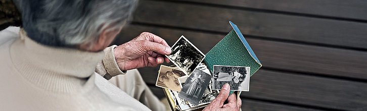 Ältere Frau schaut sich alte Fotos an